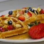 a plate of waffles with fruit on top