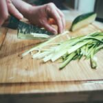 person slicing cucumber