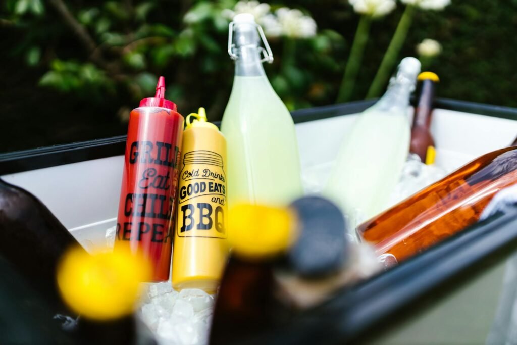 Colorful BBQ condiments and refreshing drinks in ice, perfect for a summer party.