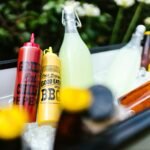 Colorful BBQ condiments and refreshing drinks in ice, perfect for a summer party.