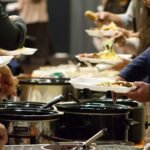 A group of people standing around a buffet line